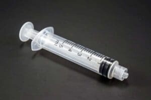 A close-up of a clear plastic syringe on a black surface.
